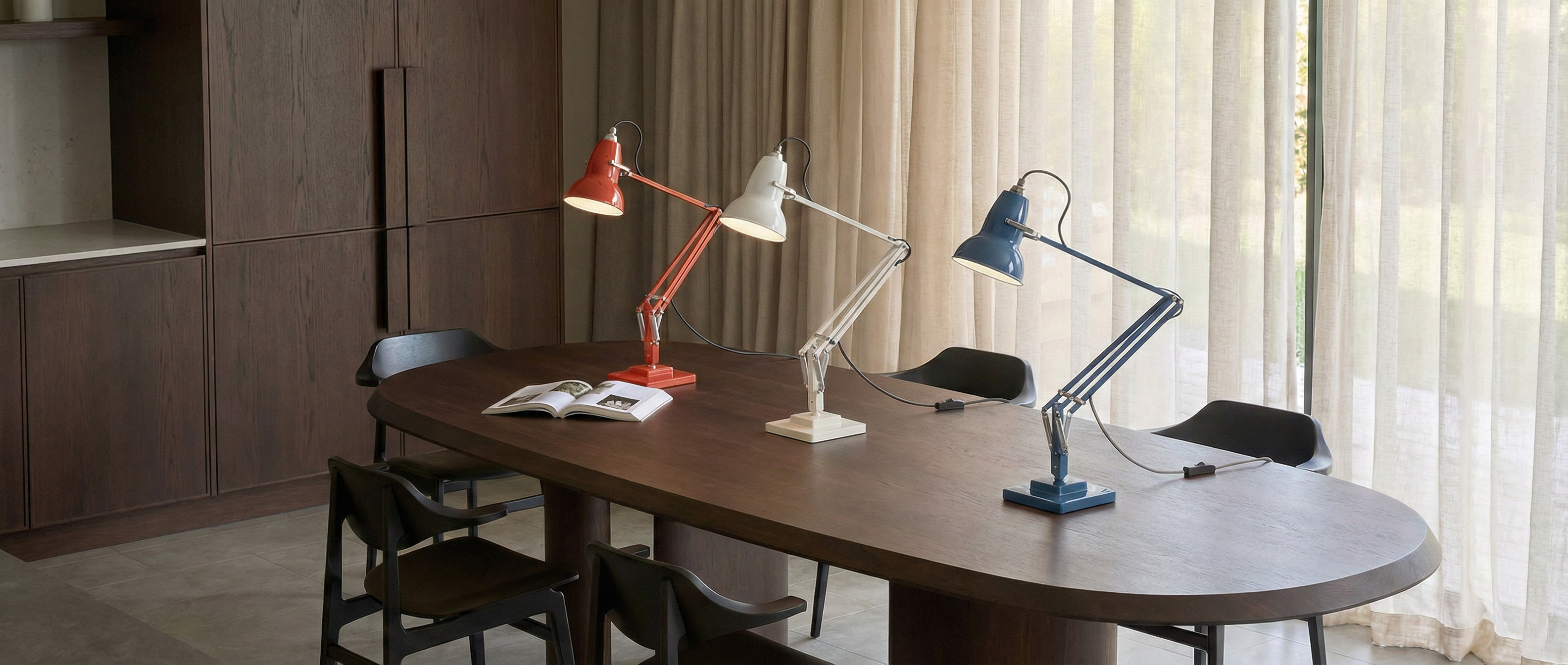 Lampe de bureau articulée Modryx sur une table avec plusieurs finitions